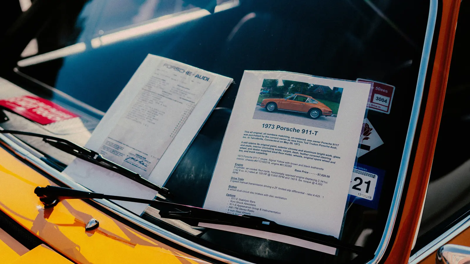 Papiere und ein Fahrzeugblatt hinter der Scheibe eines gelben Klassikers