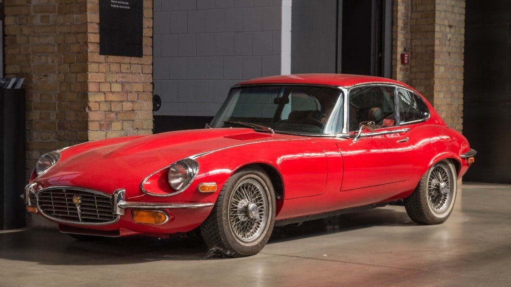 Roter Jaguar E-Type Serie 3 Coupé auf Drahtspeichenrädern in einer Halle