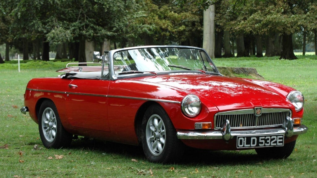 Roter MG MGB Roadster mit offenem Verdeck auf einer Wiese