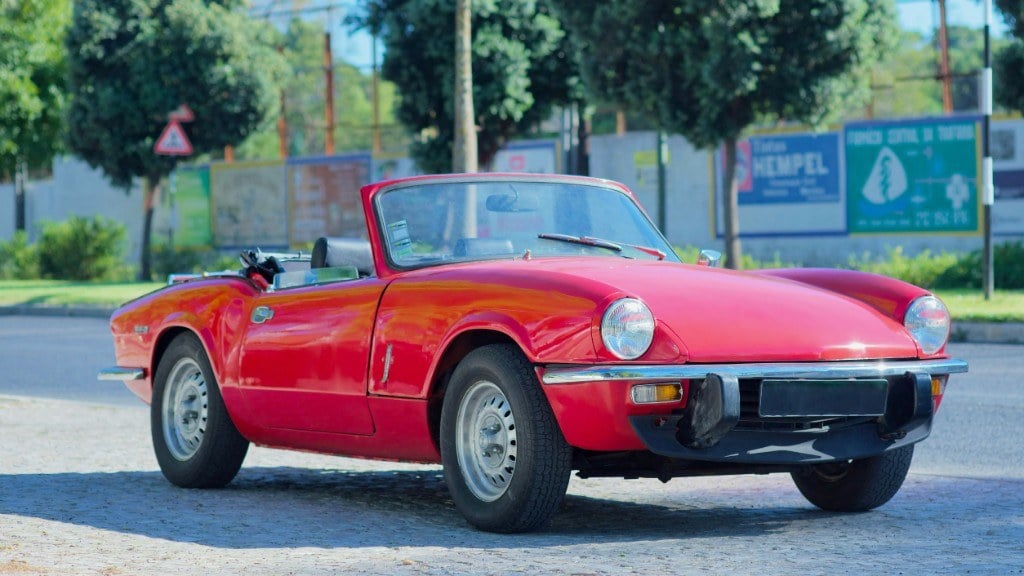 Roter Triumph Spitfire 1500 mit offenem Verdeck am Strassenrand