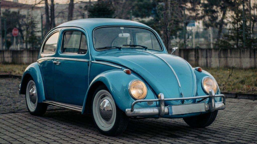 Hellblauer VW Käfer auf einem gepflasterten Platz an einem bedeckten Tag