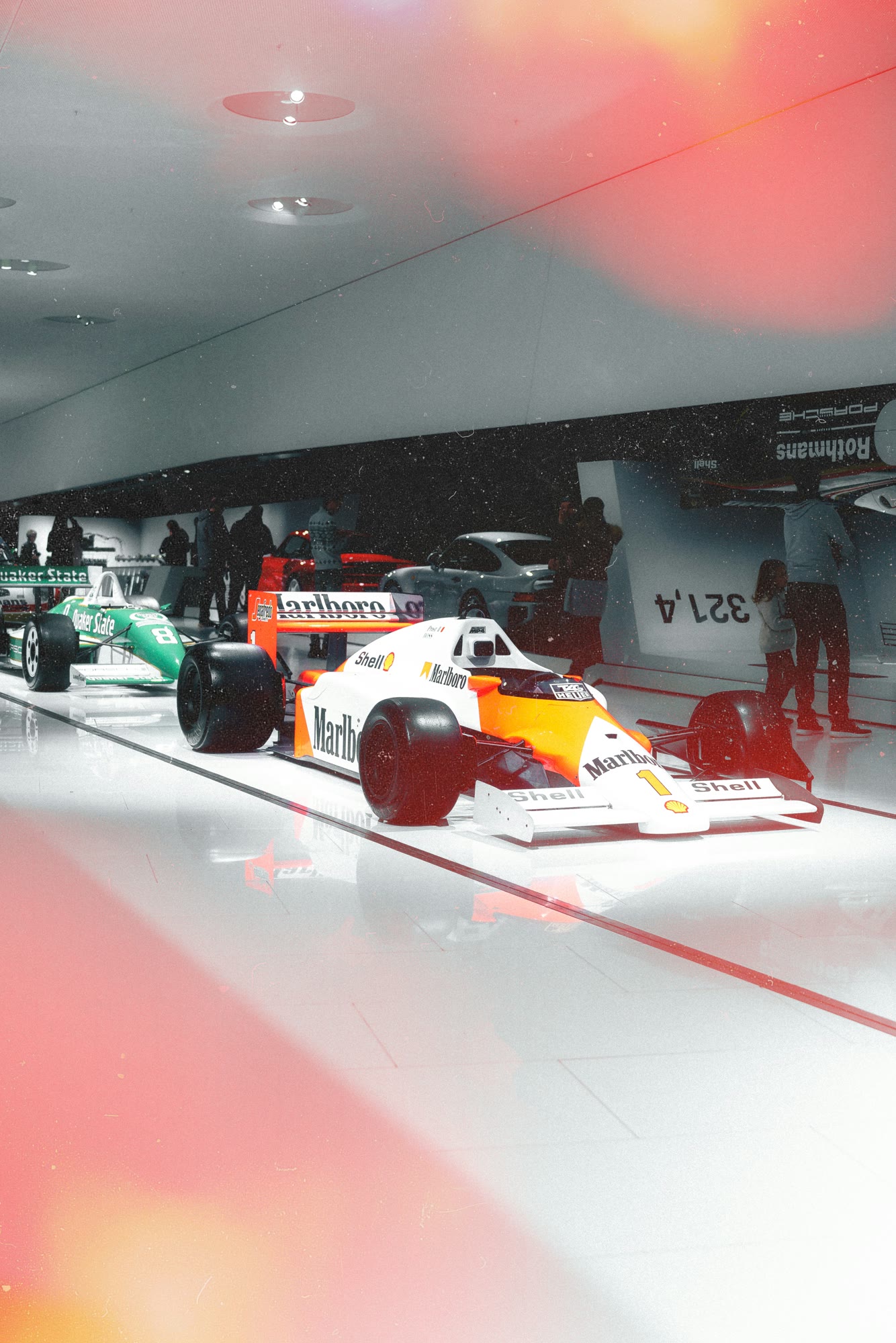 Red and white Formula 1 car with visitors in the Porsche-Museum
